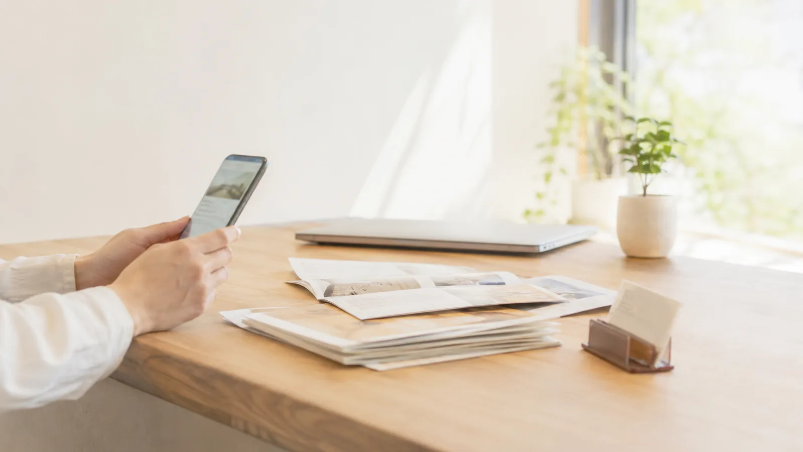 紙の会社案内を横に置いて、スマートフォンで自社のホームページを見ているところ